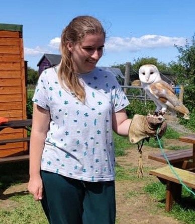 A young woman holding a barn owl on a falconry glove