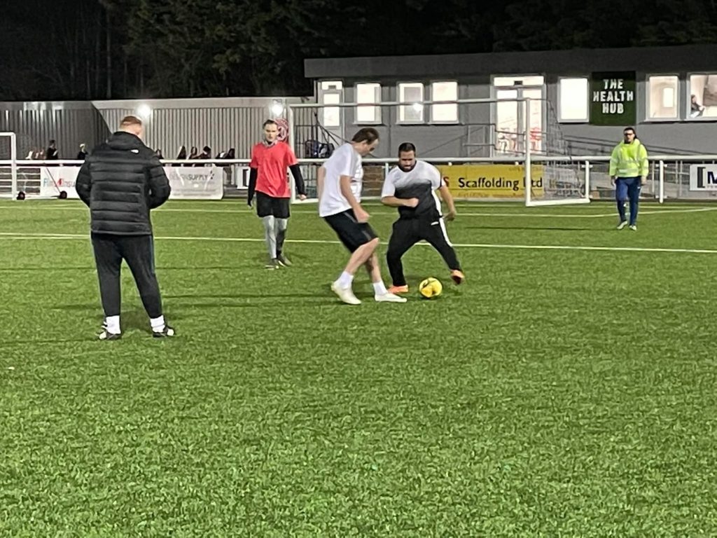 Puzzles members playing disability football on a floodlit 3G pitch