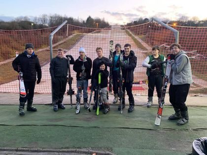 A group of Puzzles members holding skis at the bottom of a dry ski slope