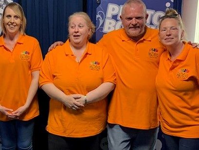 Four members of the Puzzles team in matching orange polo shirts