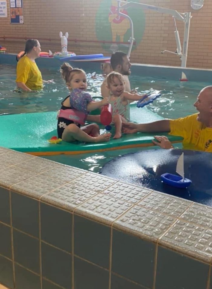 Two toddlers on a float in a hydrotherapy pool with instructors