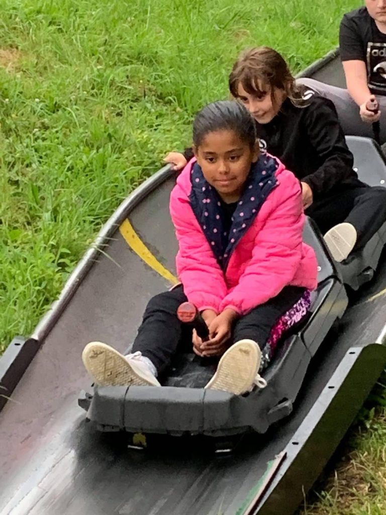 Two girls riding a toboggan run together